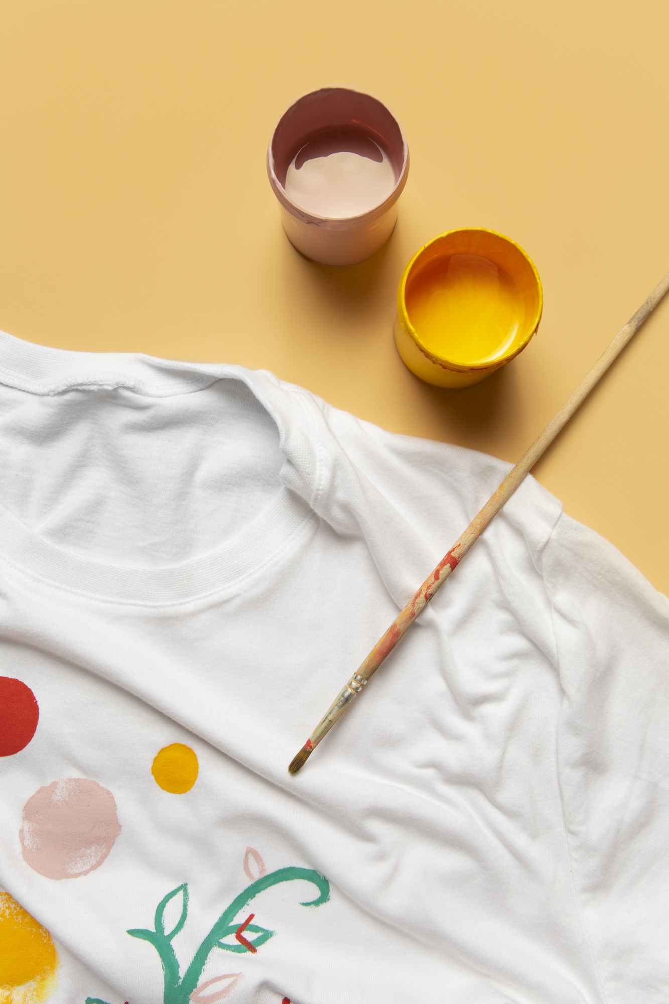 Camiseta pintada à mão com potes de tinta ao lado