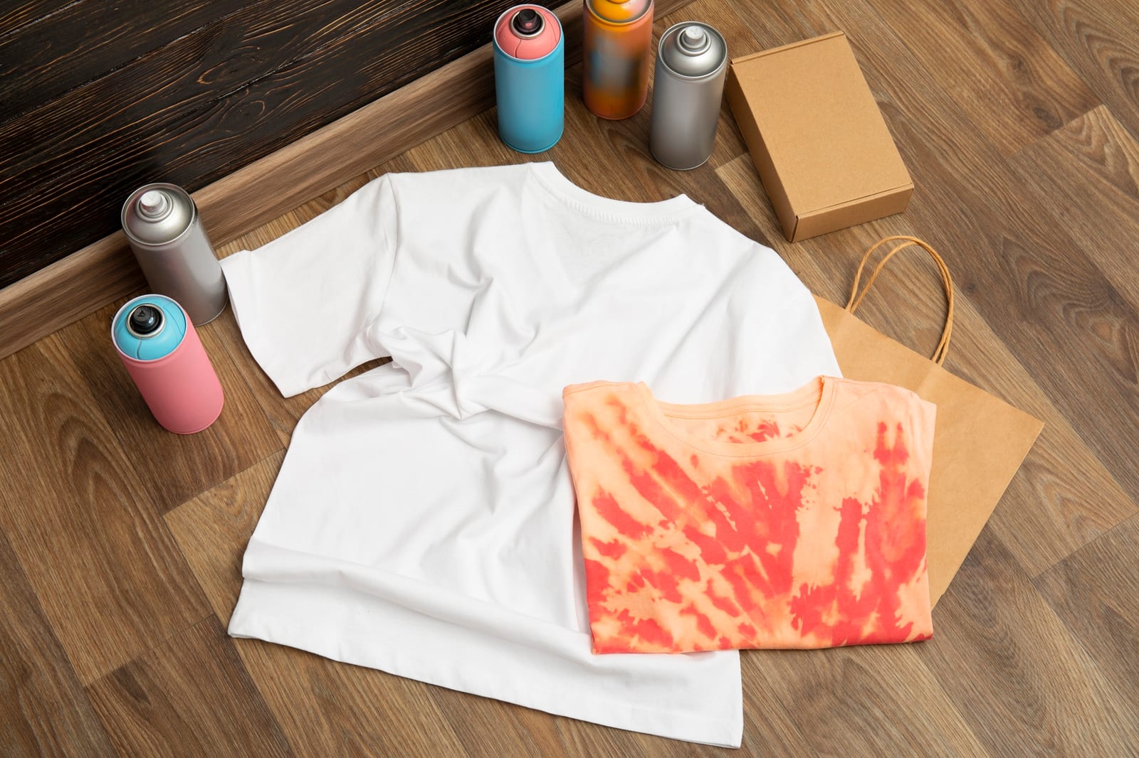 Camisetas lisas e tingidas dispostas com latas de spray